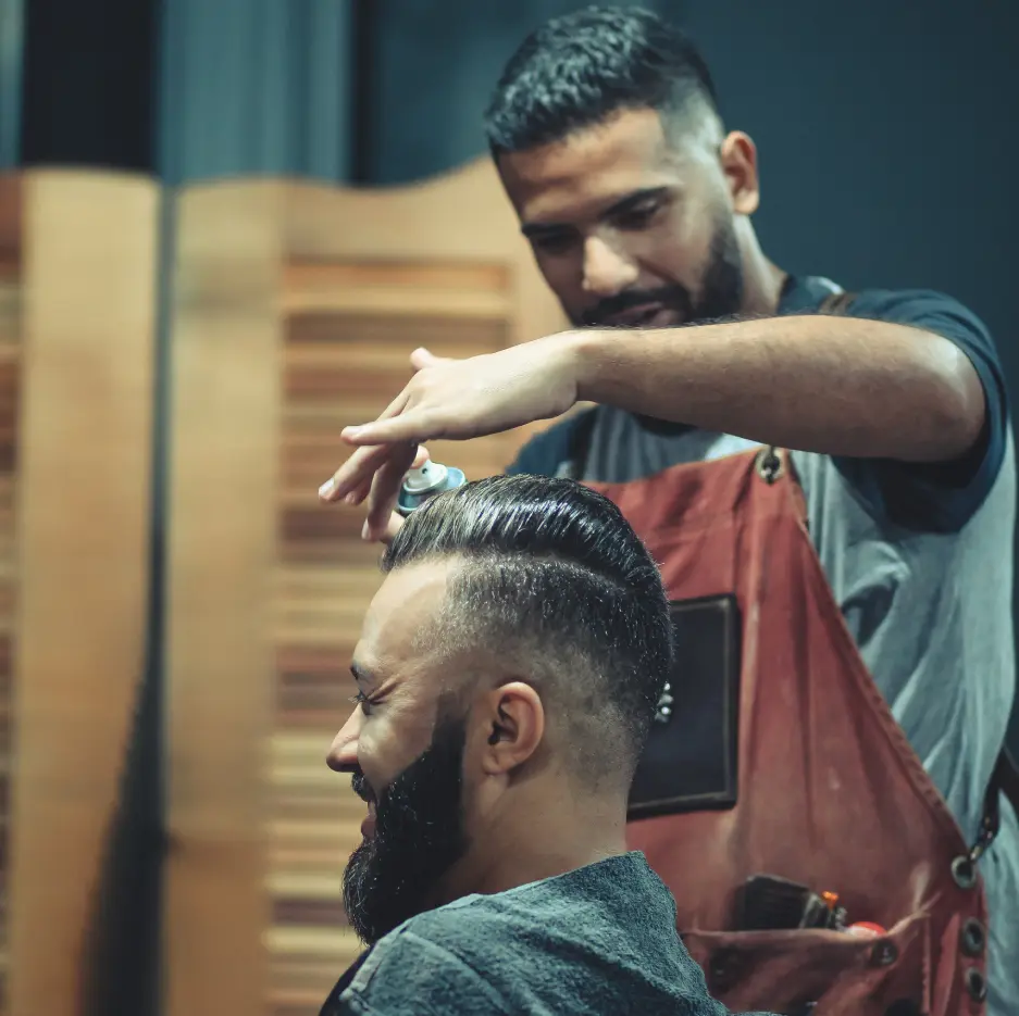 A man getting his hair cut by another man.